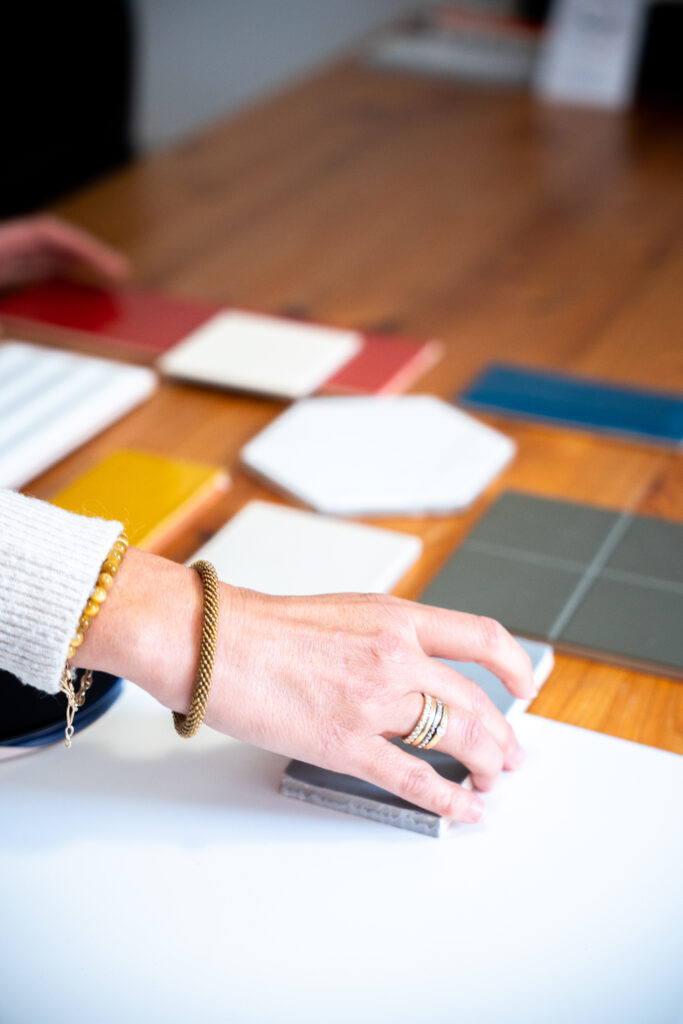 Main sélectionnant des échantillons de carrelage réemployé sur table en bois